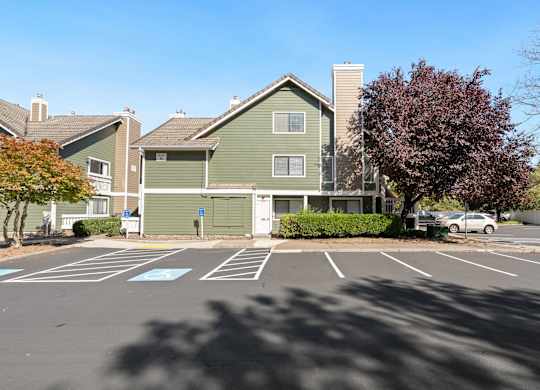 A parking lot with a green building in the background.