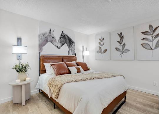 a bedroom with a bed and paintings of horses at AVIA Lofts on Liberty Ridge Apartments, Jacksonville
