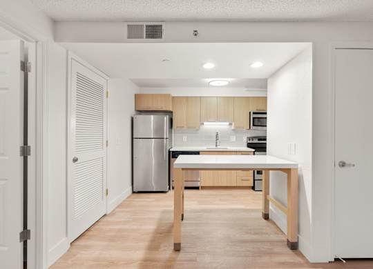 a kitchen with a large island and a stainless steel refrigerator at AVIA Lofts on Parkway Apartments, Washington, 98662