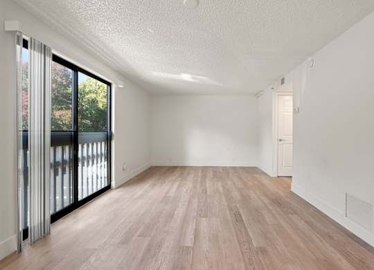 an empty living room with a sliding glass door to a balcony at AVIA Lofts on Parkway Apartments, Vancouver, Washington