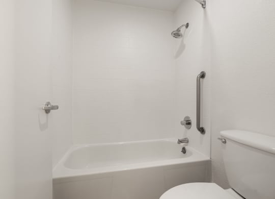 a white bathroom with a tub and a toilet at AVIA Lofts on Parkway Apartments, Washington, 98662
