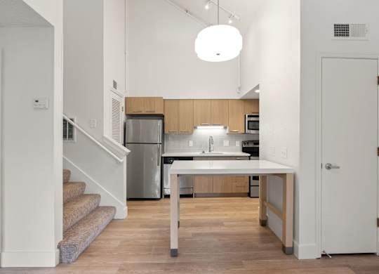 a kitchen with a white table and a stainless steel refrigerator at AVIA Lofts on Parkway Apartments, Washington