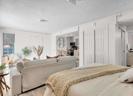 a bedroom with a bed and a living room with a couch at AVIA Lofts on Liberty Ridge Apartments, Jacksonville, Florida