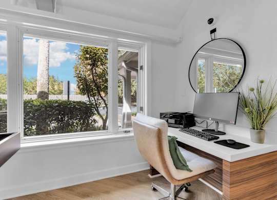 a home office with a large window and a desk with a computer at AVIA Lofts on Liberty Ridge Apartments, Jacksonville, FL, 32256