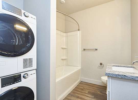A white washing machine and dryer in a small bathroom at Brickside Heights Apartments, Millcreek