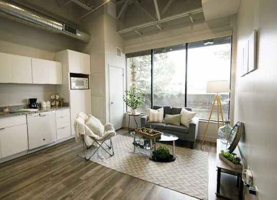A modern living room with a grey floor and white walls at Brickside Heights Apartments, Millcreek