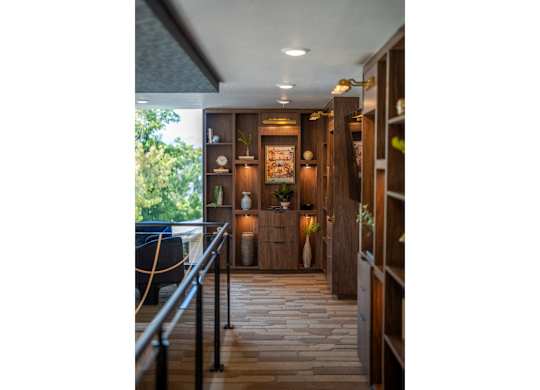 A hallway with a black railing and wooden floors.