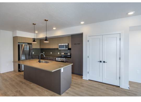 A modern kitchen with a sink, stove, and refrigerator.