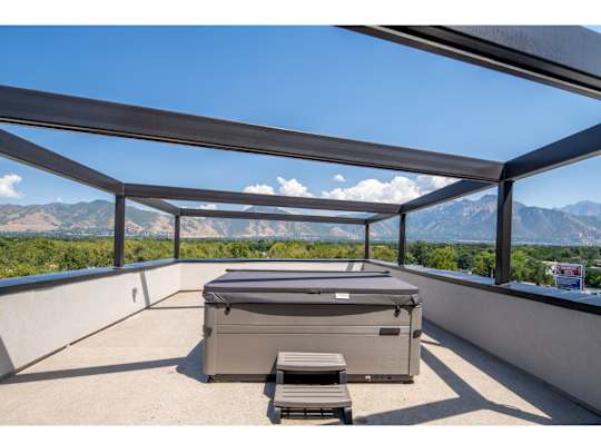 A hot tub is on a patio with mountains in the background.