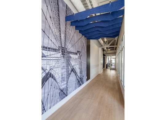 A long hallway with a blue ceiling and a wall with a black and white drawing on it.