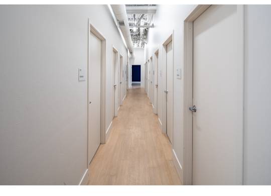 A long hallway with doors on both sides and a blue door at the end.