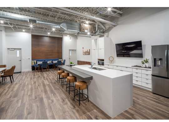 A modern kitchen with a long bar and stools.
