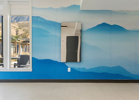 a blue wall with mountains painted on it and a door at The Flats at Riverwoods, Provo, UT