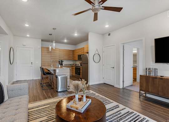 a living room with a couch and a table in front of a kitchen at The Flats at Riverwoods, Provo