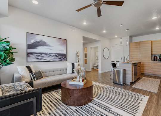 an open living room with a kitchen and a ceiling fan at The Flats at Riverwoods, Provo