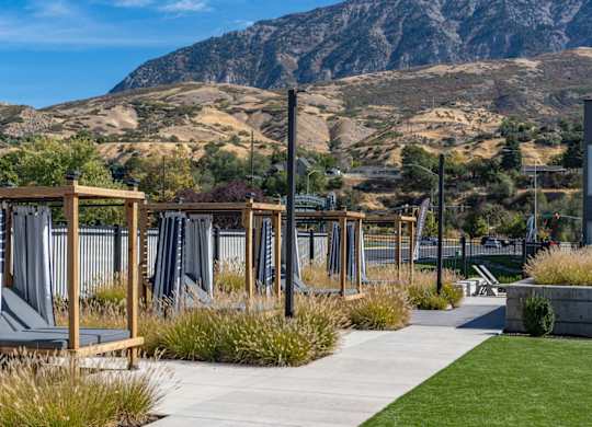 a view of the mountains from a park with benches and grass at The Flats at Riverwoods, Provo, UT, 84604