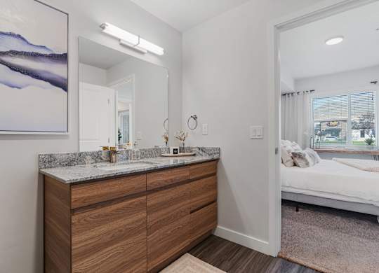 a bathroom with a vanity and a mirror and a bedroom with a bed at The Flats at Riverwoods, Provo, 84604