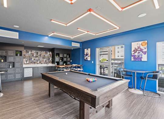 A pool table is in the middle of a room with a blue wall.