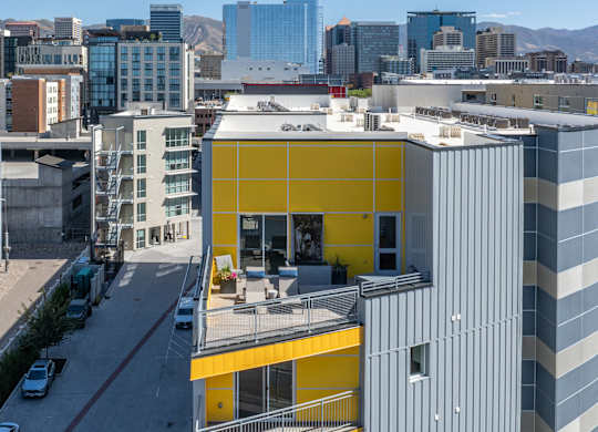 a building with a yellow facade and a city in the background at Paperbox Lofts, Salt Lake City, Utah