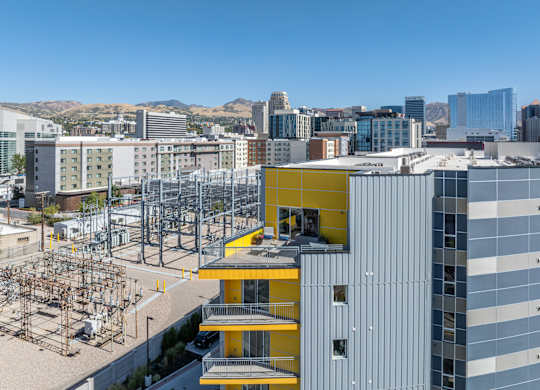 A modern building with a yellow section in the middle is in the foreground of a cityscape.