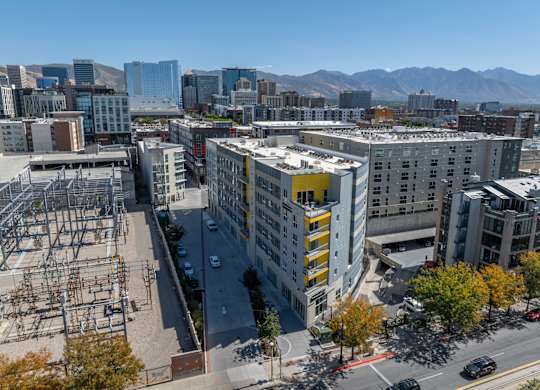 A cityscape with a large building in the foreground and mountains in the background.