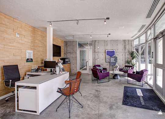 A modern office space with a white desk, purple chairs, and a wooden wall.
