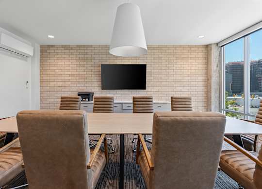 a conference room with a table and chairs and a tv on the wall at The Revival, Salt Lake City, UT, 84101