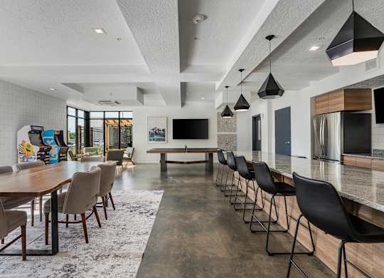a large dining room with a long table and chairs and a kitchen and living room at The Flats at Riverwoods, Provo, UT, 84604