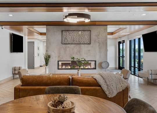 a living room with a couch and a table and a fireplace at The Flats at Riverwoods, Provo, UT, 84604