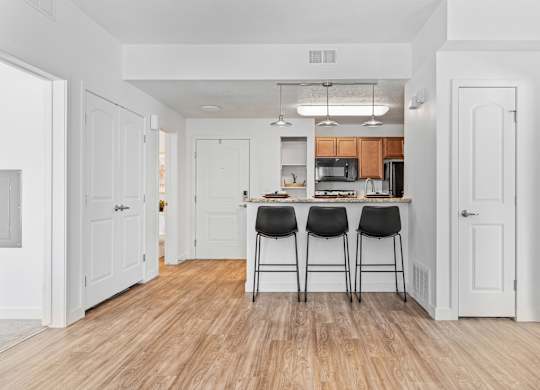 the living room and kitchen of a house with white walls and wood floorsat The View on 20th, Ogden, 84401