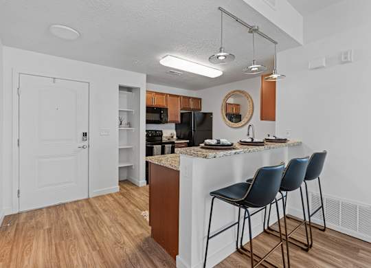 a kitchen with bar stools and a breakfast bar with three stoolsat The View on 20th, Ogden, UT