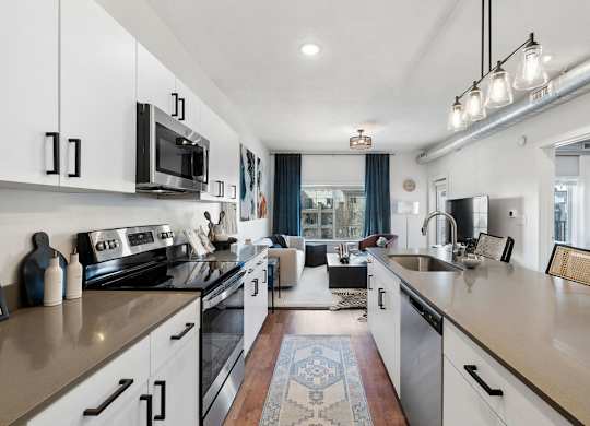 an open kitchen with counters and appliances and a living room at The Revival, Salt Lake City, 84101