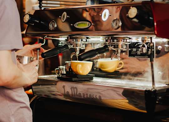 A person is making a cup of coffee at a coffee machine.