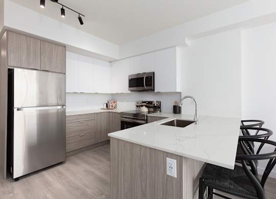 A modern kitchen with a white countertop and a stainless steel refrigerator.