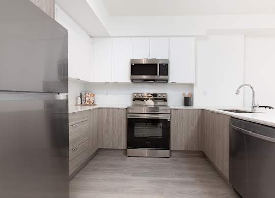A modern kitchen with a refrigerator, oven, and sink.