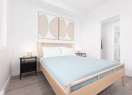 A bedroom with a bed, nightstand, and lamp.