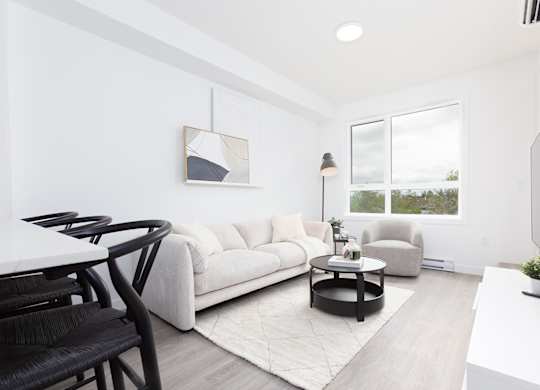 A modern living room with a white couch, a coffee table, and a television.