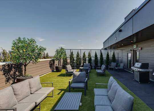 A patio with grey couches and a grill.