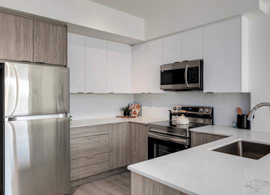 A modern kitchen with a stainless steel refrigerator, microwave, and oven.