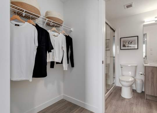 Clothes hanging on a rack in a small bathroom.