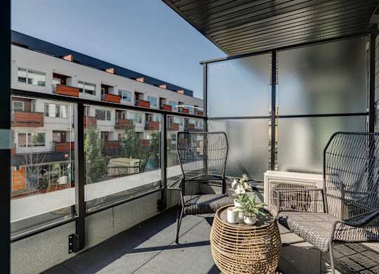 A balcony with a chair and table with a view of apartment buildings.