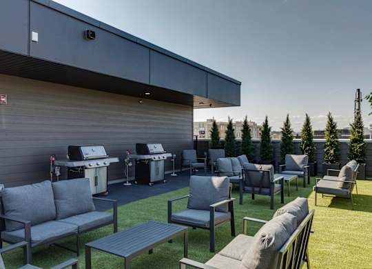 A patio area with grey couches and tables.