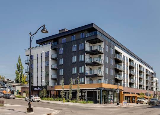 A modern multi-story building with a parking lot in front.