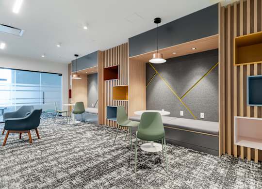 A room with a grey carpet and wooden paneling.