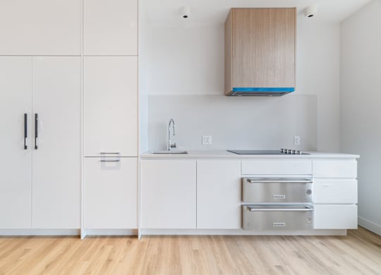 A kitchen with white cabinets and a wooden hood.