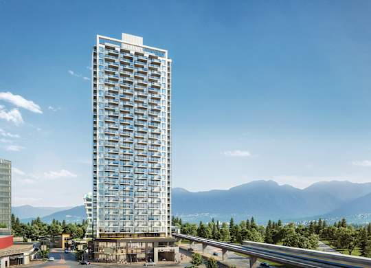 A tall building with many windows stands in front of a mountain range.