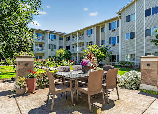 A patio with a table and chairs is surrounded by apartment buildings.