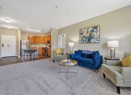 A living room with a blue couch and a grey rug.