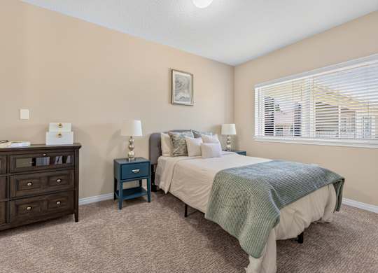 A bedroom with a bed, nightstand, and dresser.