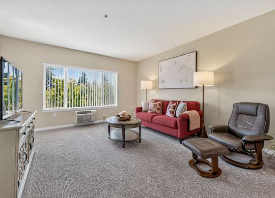 A living room with a red couch, a chair, and a coffee table.
